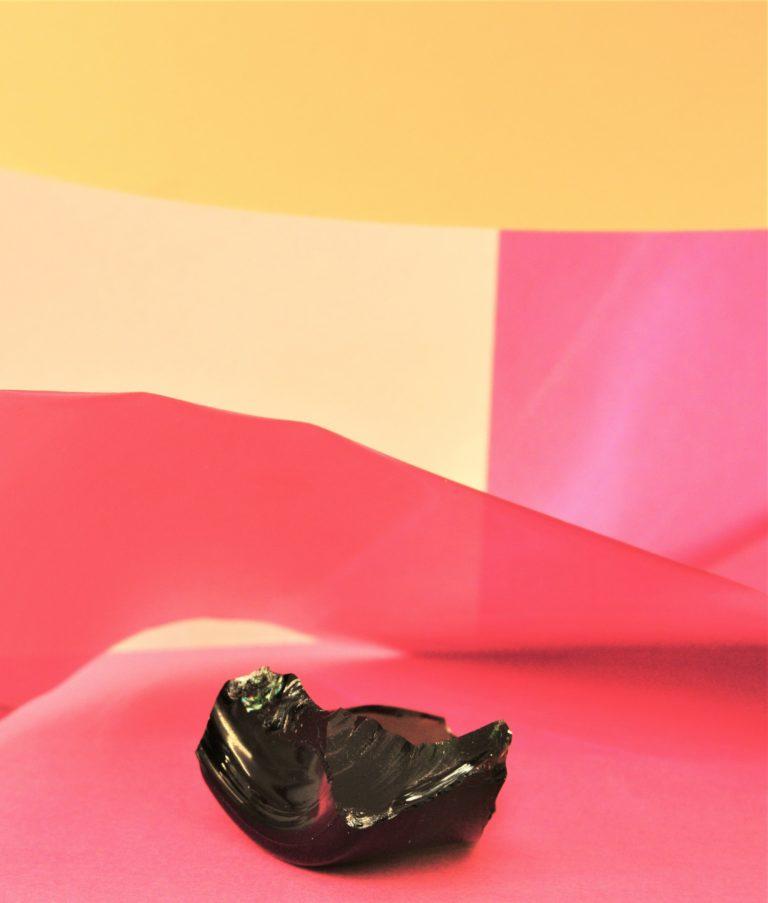 Éclat de verre devant une toile aux couleurs jaune et rose